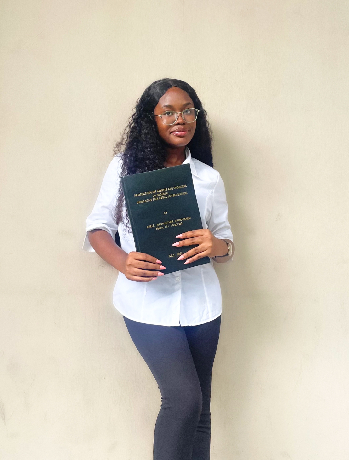 Mary-Esther holding her LLB dissertation